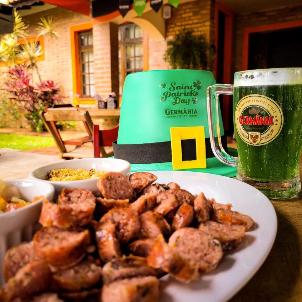 Prato de linguiça assada, caneca de cerveja verde e um chapéu de Saint Patrick's Day