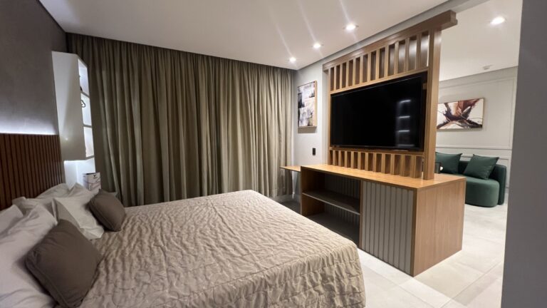 Quarto de hotel mostrando a cama, tv e sofá
