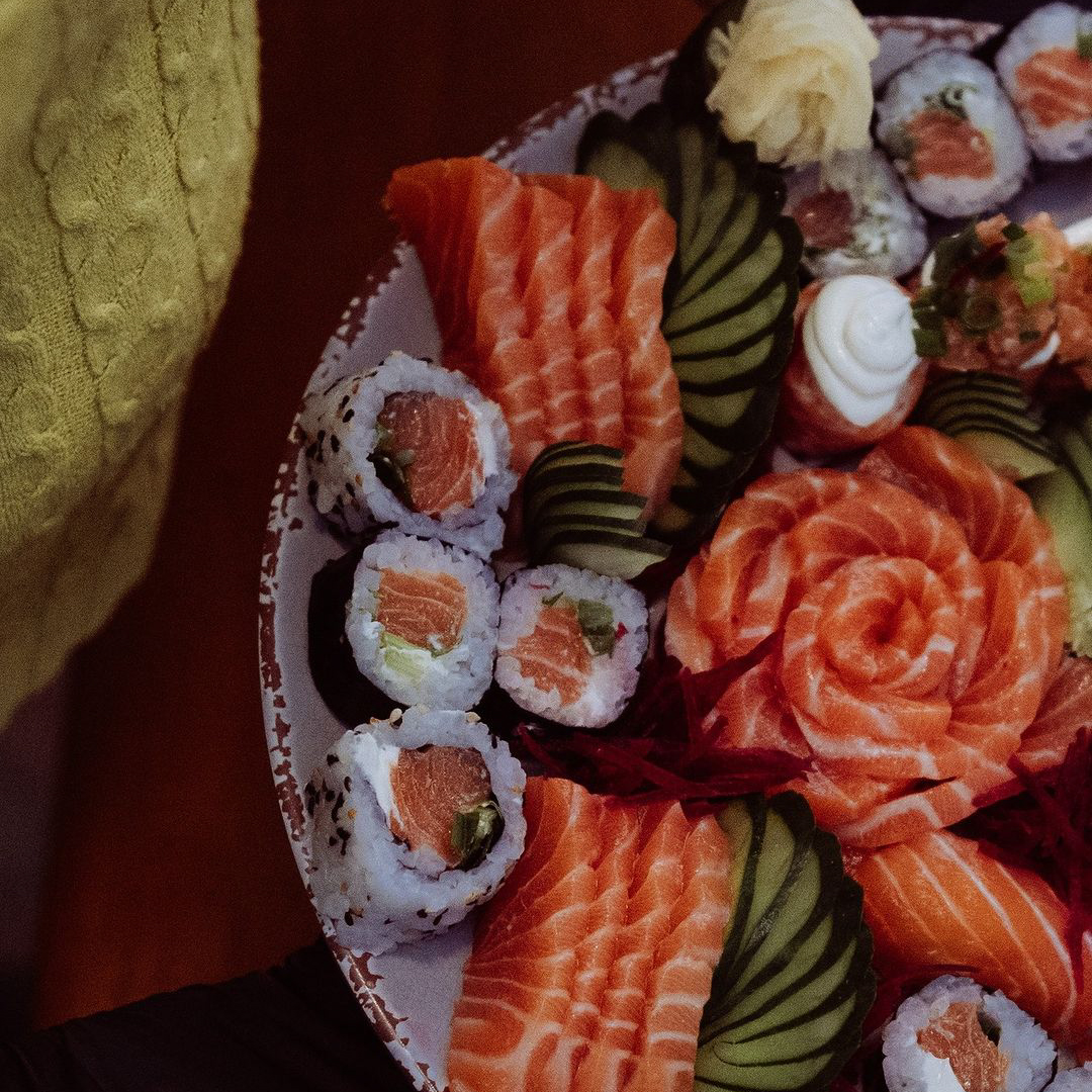 Pessoa carregando um prato com diversas peças de sushi diferentes