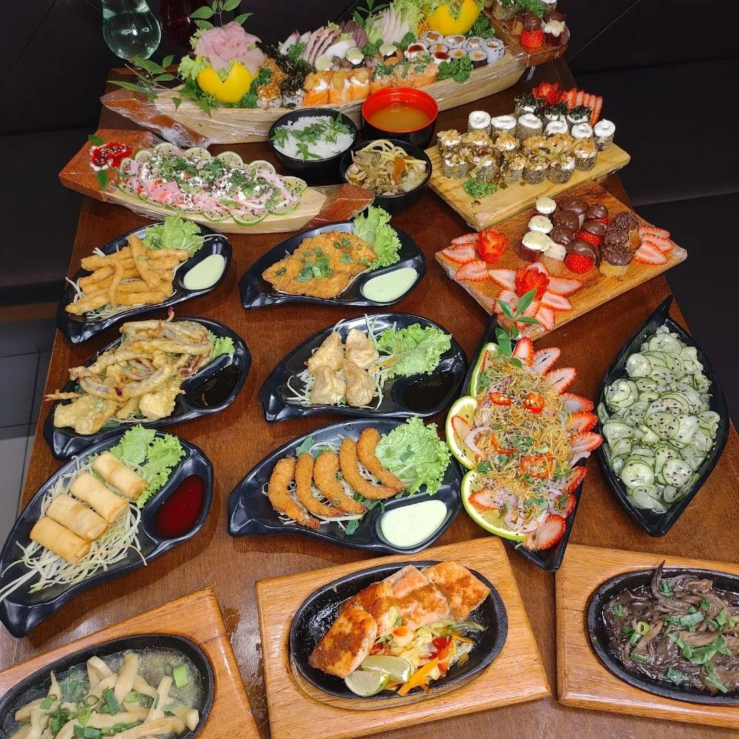 Mesa com uma grande quantidade de pratos de comida japonesa
