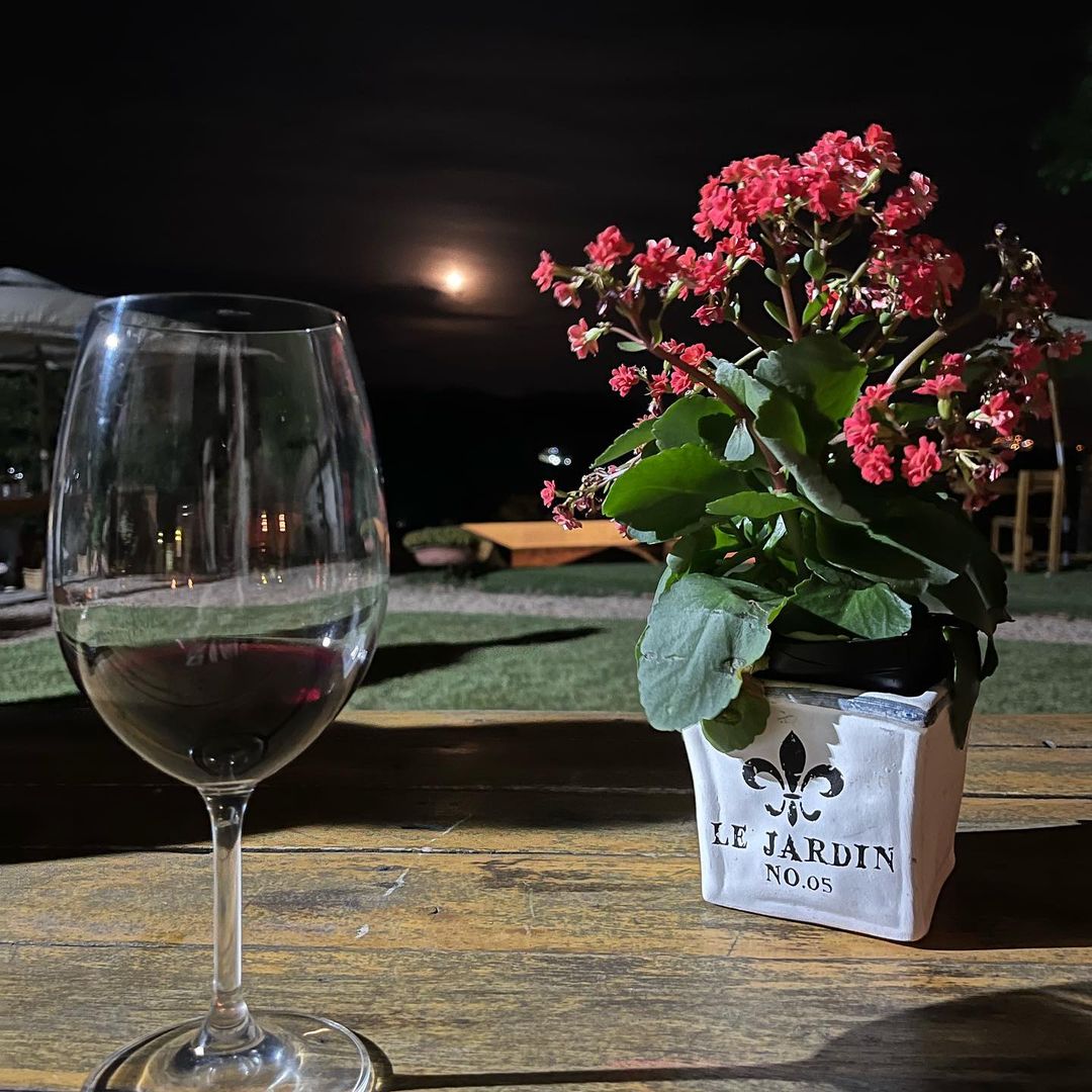 Taça de vinho sobre mesa, céu com lua cheia ao fundo