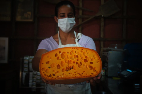 Mulher segurando grande queijo